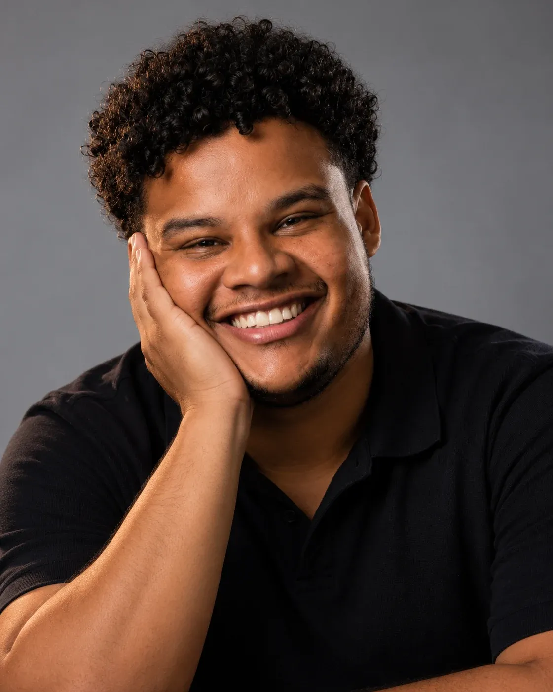 Vitor Hugo, fundador da Regência Comunicação, sorrindo com a mão no rosto, em retrato de estúdio
